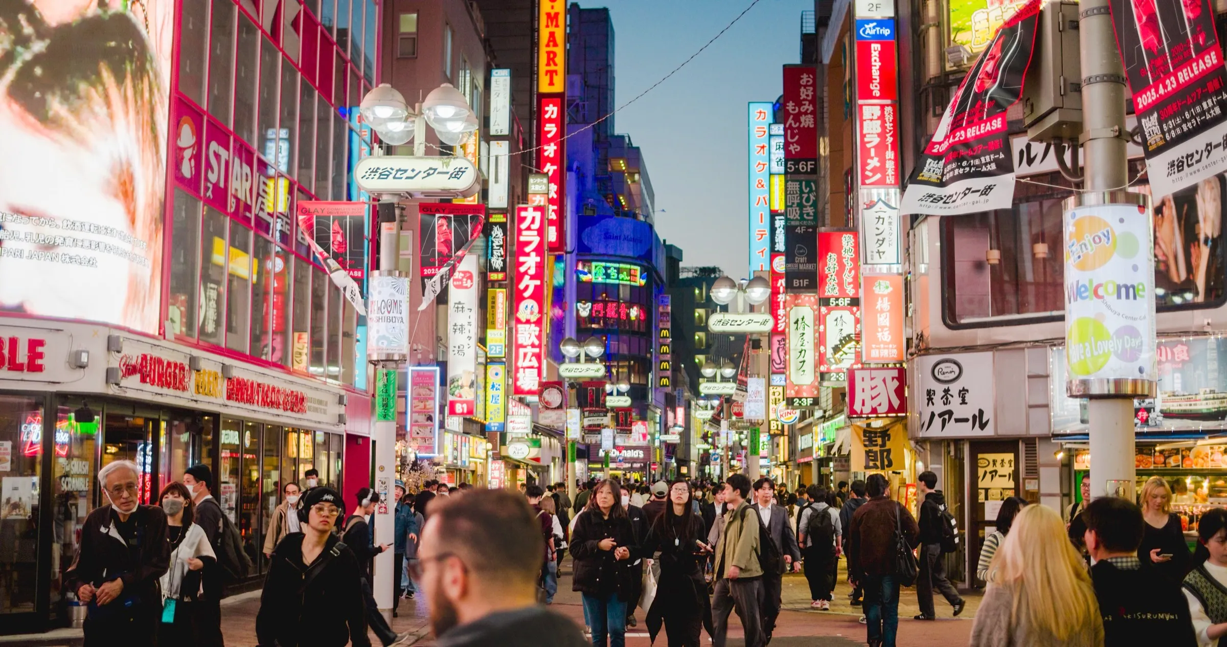 A neon-lit street in Tokyo's Shinjuku at dusk